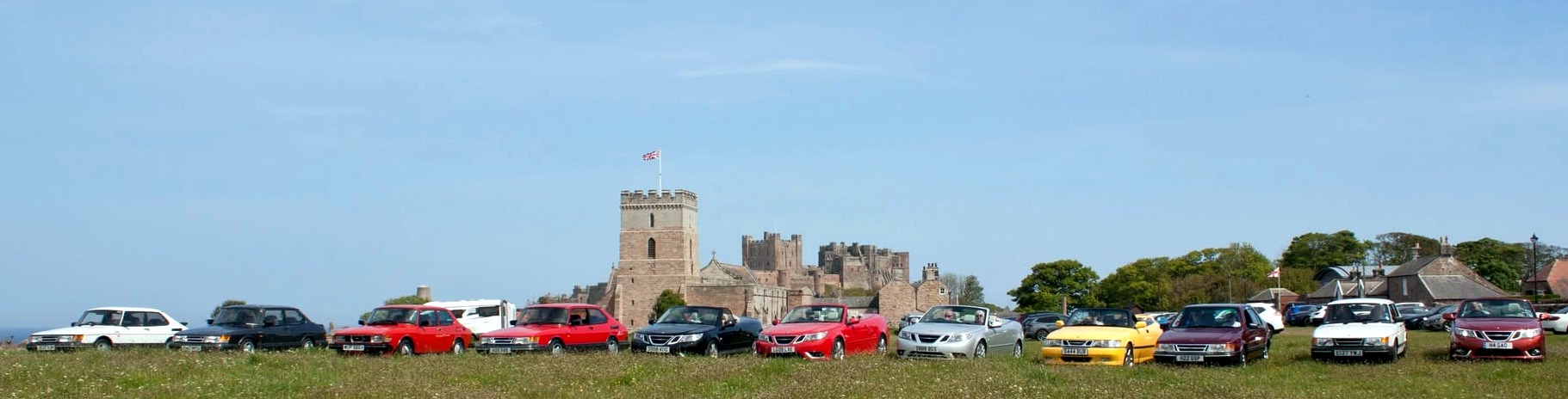North East Saab Events cars lined up by Bamburgh Castle